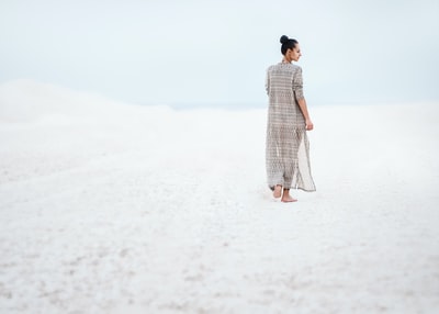 女人在灰色的裙子走在沙滩上
